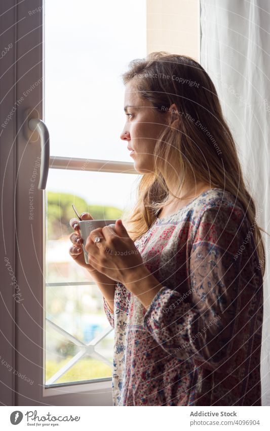 Mädchen im Hemd mit einer Tasse Kaffee oder Tee, das morgens aus dem Fenster schaut Frau hübsch wach Freude Schönheit im Innenbereich Ansicht heimwärts ruhen