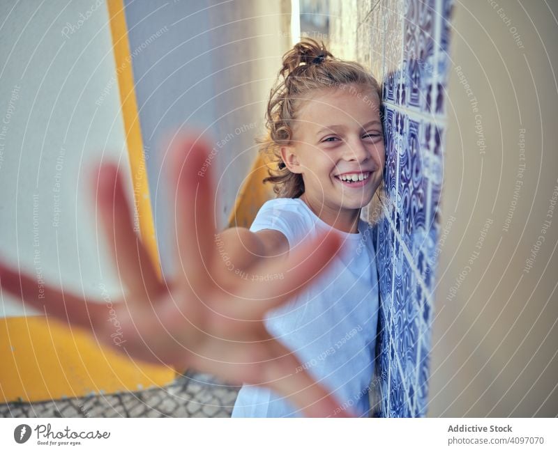 Lächelndes Kind auf der Straße stehend Portugal Inhalt Stehen fettarm Wand Glück Kindheit Sonnenlicht Freizeit heiter jung sich[Akk] entspannen ruhen Urlaub