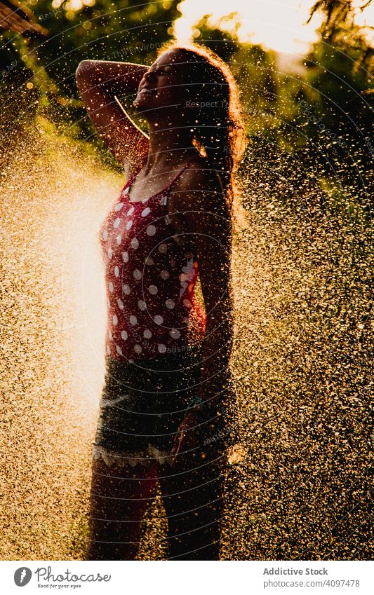 Fröhlicher Teenager hat Spaß mit Wasserstrahl Garten Düsenflugzeug Lachen Sommer Wochenende Mädchen aufgeregt Lifestyle ruhen sich[Akk] entspannen strömen