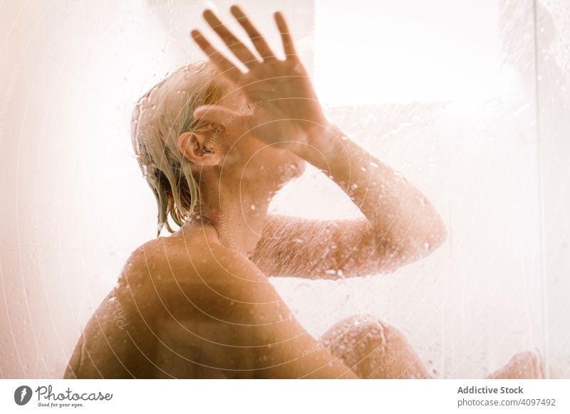 Anonyme Frau in Duschkabine sitzend Dusche nass Glas durchsichtig berühren Abtrennung Bad Wasser Tropfen jung nackt Pflege Körper Sauberkeit übersichtlich