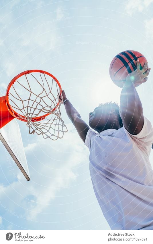 Afroamerikanischer Sportler hängt auf Basketball-Runde Ball tretend Netz Slam Dunk Spiel Spieler Stadion Spielen Sportbekleidung Aktivität Feld männlich