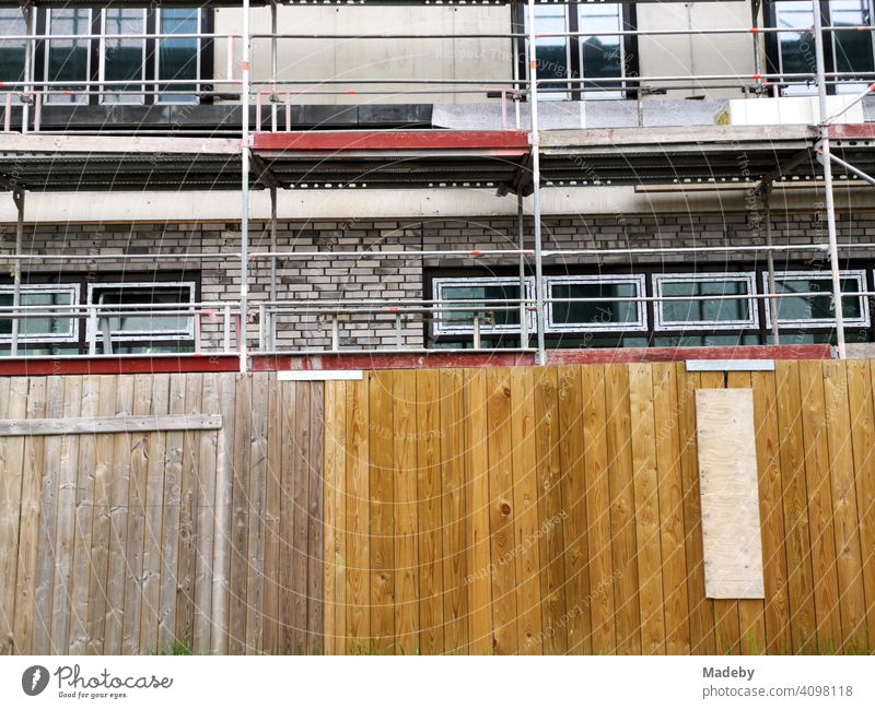 Bauzaun aus Holz vor dem Neubau eines Wohnhaus mit Baugerüst am ehemaligen Hafen in Offenbach am Main in Hessen Baustelle Holzzaun Zaun Sichtschutz Bauen