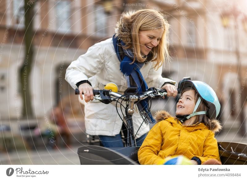 Junge Frau und ihr Sohn fahren mit dem Fahrrad in einer Stadt jung tragend Schutzhelm Fahrradfahren Winter Herbst Mutter Familie Eltern Verwandte Kind Kinder