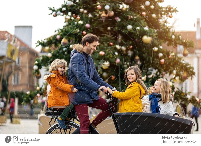 Junge Familie fährt in einem Lastenfahrrad während Weihnachten Lastenrad Fahrrad Fahrradfahren Verkehr Dreirad Gesundheit aktiv Zyklus Radfahren modern