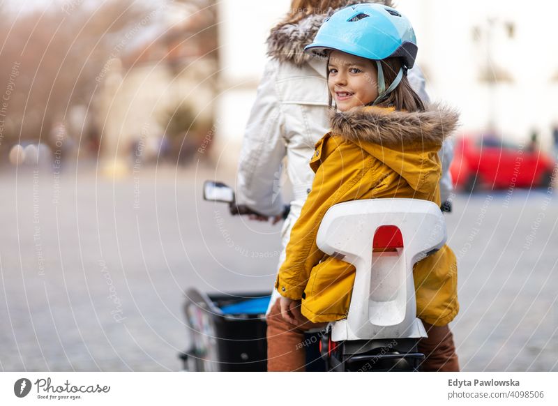 Junge Frau und ihr Sohn fahren mit dem Fahrrad in einer Stadt jung tragend Schutzhelm Fahrradfahren Winter Herbst Mutter Familie Eltern Verwandte Kind Kinder