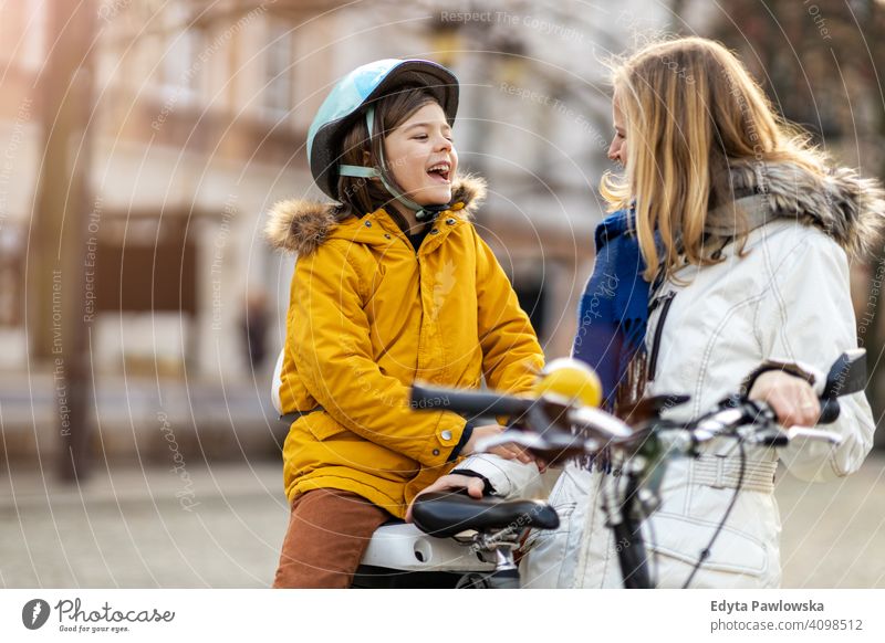 Junge Frau und ihr Sohn fahren mit dem Fahrrad in einer Stadt jung tragend Schutzhelm Fahrradfahren Winter Herbst Mutter Familie Eltern Verwandte Kind Kinder