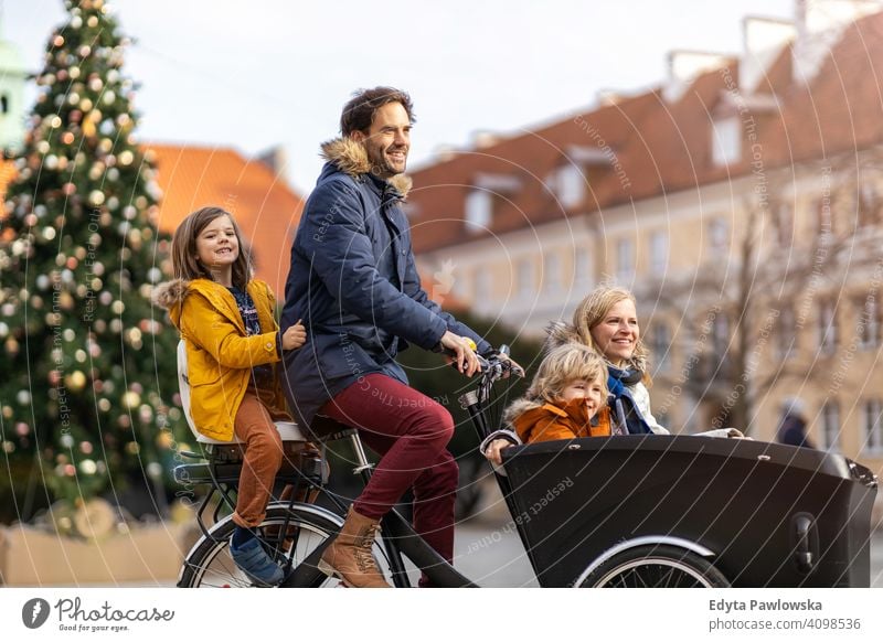 Junge Familie fährt in einem Lastenfahrrad während Weihnachten Lastenrad Fahrrad Fahrradfahren Verkehr Dreirad Gesundheit aktiv Zyklus Radfahren modern