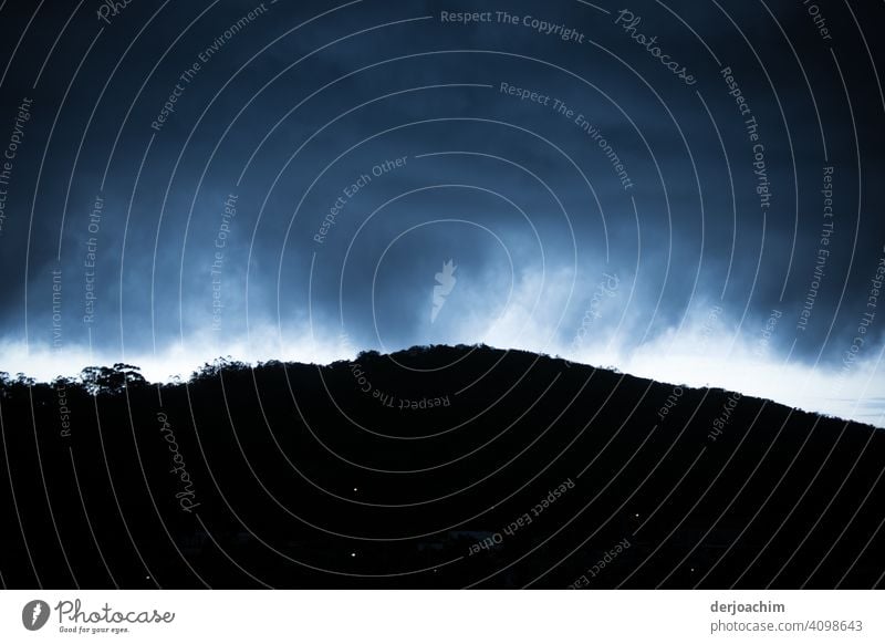 Unwetter über dem Hügel  . Nur noch ein kleiner heller Schein über den blau schwarzen Regenwolken , dem Regenwald.  Als wollte die Welt untergehen. Wetter