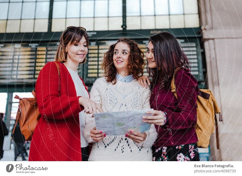 Gruppe von drei jungen kaukasischen Frauen am Bahnhof lesen eine Karte. Reisen und Freundschaft Konzept reisen Freunde Landkarte Zusammensein Spaß 3 Holzplatte