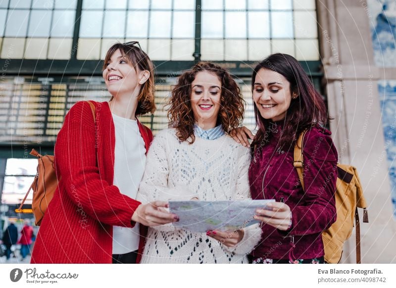 Gruppe von drei jungen kaukasischen Frauen am Bahnhof lesen eine Karte. Reisen und Freundschaft Konzept reisen Freunde Landkarte Zusammensein Spaß 3 Holzplatte