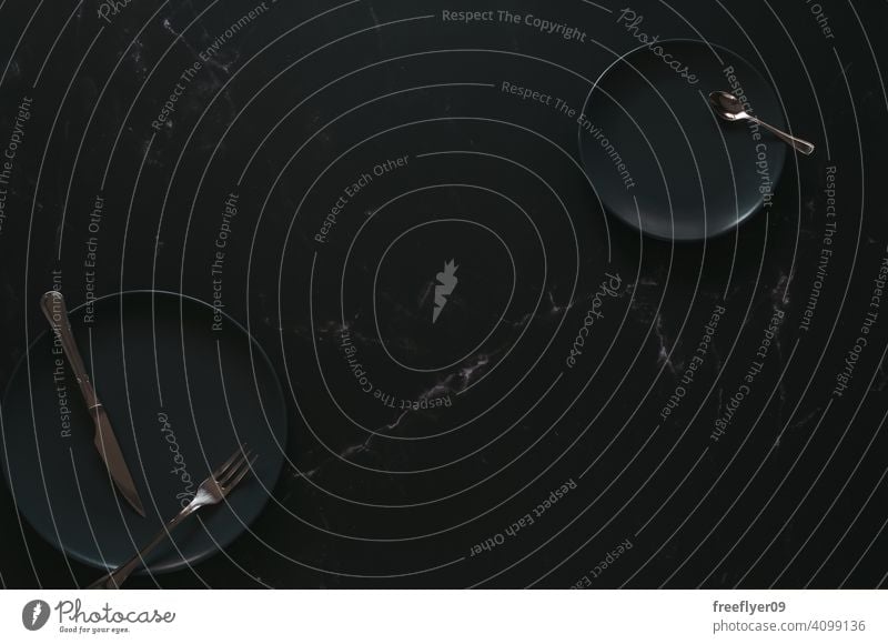 Flachlegung mit leeren Luxustellern Attrappe Teller Besteck schwarz dunkel Reichtum luxuriöses Lebensmittel Textfreiraum Murmel Stein flache Verlegung noch