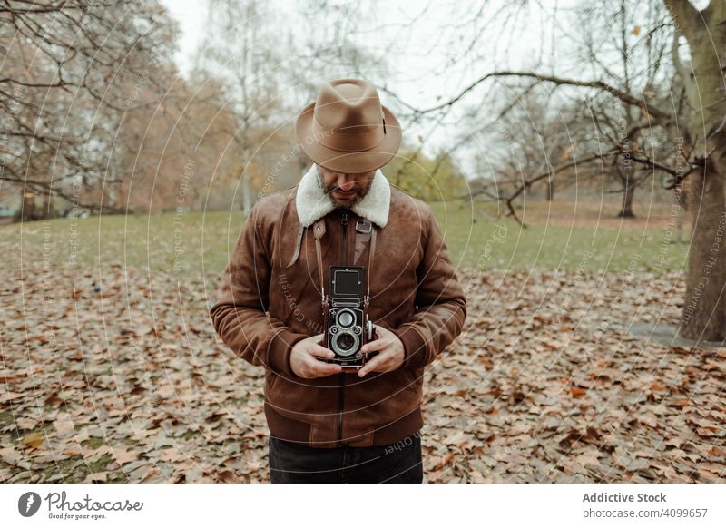 Männlicher Fotograf steht im Herbstpark Mann Fotoapparat retro Park London lässig friedlich Erwachsener männlich Großbritannien England altehrwürdig Blatt