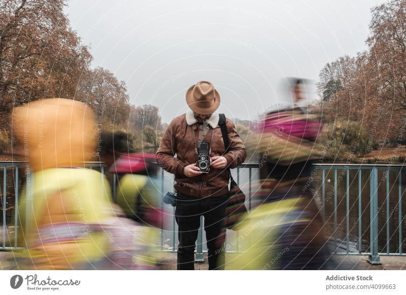 Männlicher Tourist mit altertümlicher Kamera am Fluss Fotoapparat Park Brücke Mann Herbst Windstille London Großbritannien reisen Wasser retro altehrwürdig