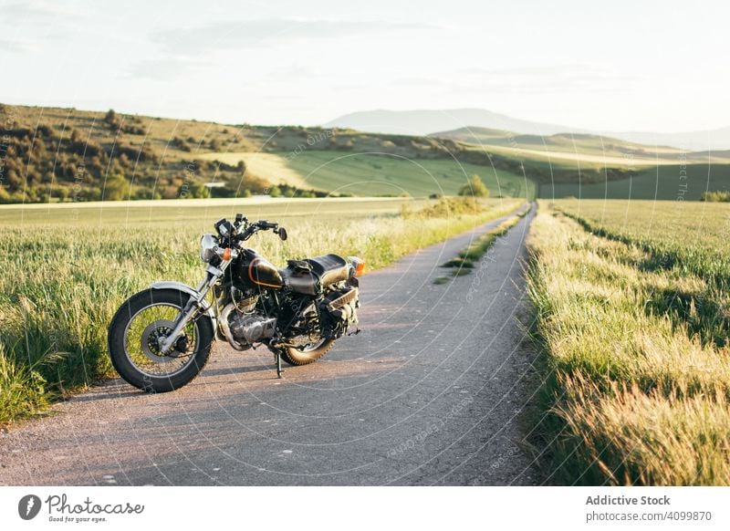 Motorrad auf Landstraße bei Gras Straße Feld Landschaft sonnig tagsüber friedlich Asphalt Weg Fahrzeug Verkehr Wiese modern Zeitgenosse niemand Windstille ruhig