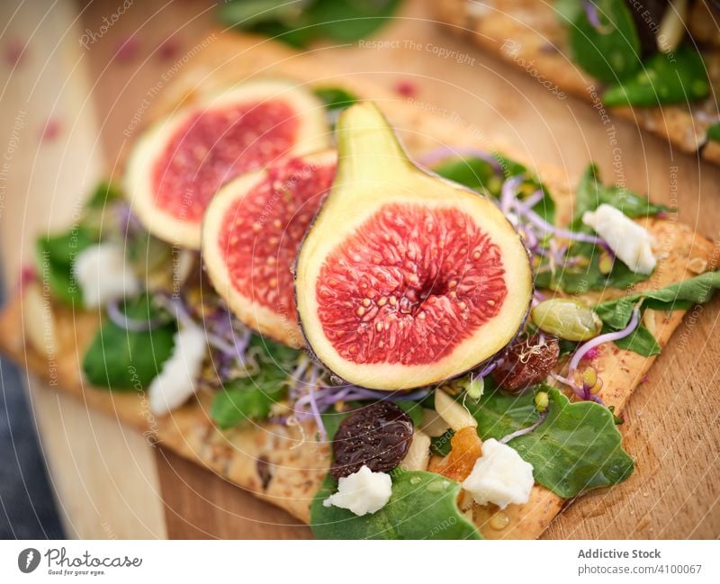 Reife Feigen zwischen Kräutern und Blumen auf dem Schneidebrett Rucolasalat frisch Frucht Lebensmittel Erfrischung Mahlzeit Roggenbrot exotisch Gemüse Scheibe