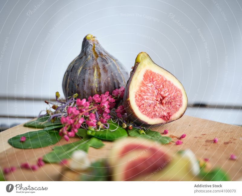 Reife Feigen zwischen Kräutern und Blumen auf dem Schneidebrett Rucolasalat frisch Frucht Lebensmittel Erfrischung Mahlzeit Roggenbrot exotisch Gemüse Scheibe