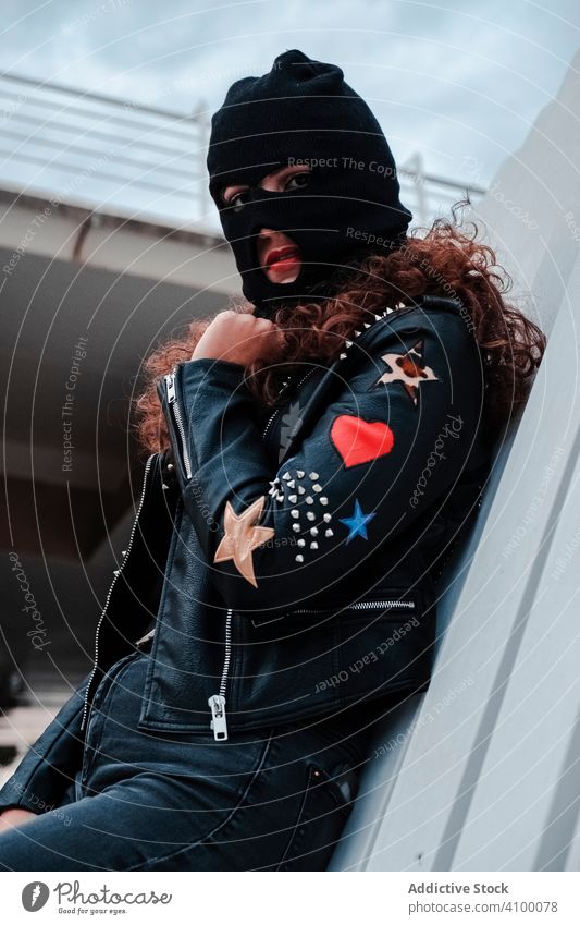 Frau mit Sturmhaube und schwarzer Lederjacke Mundschutz Jacke Felsen Stil streifen urban Straße brünett Mode Großstadt Outfit jung trendy unterirdisch Kleidung