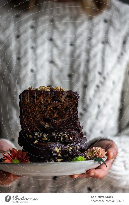 Crop Frau zeigt frische und Blumen Brot Spielfigur Banane führen Teller süß Dessert geschmackvoll lecker Lebensmittel Snack Leckerbissen Gebäck Kuchen organisch