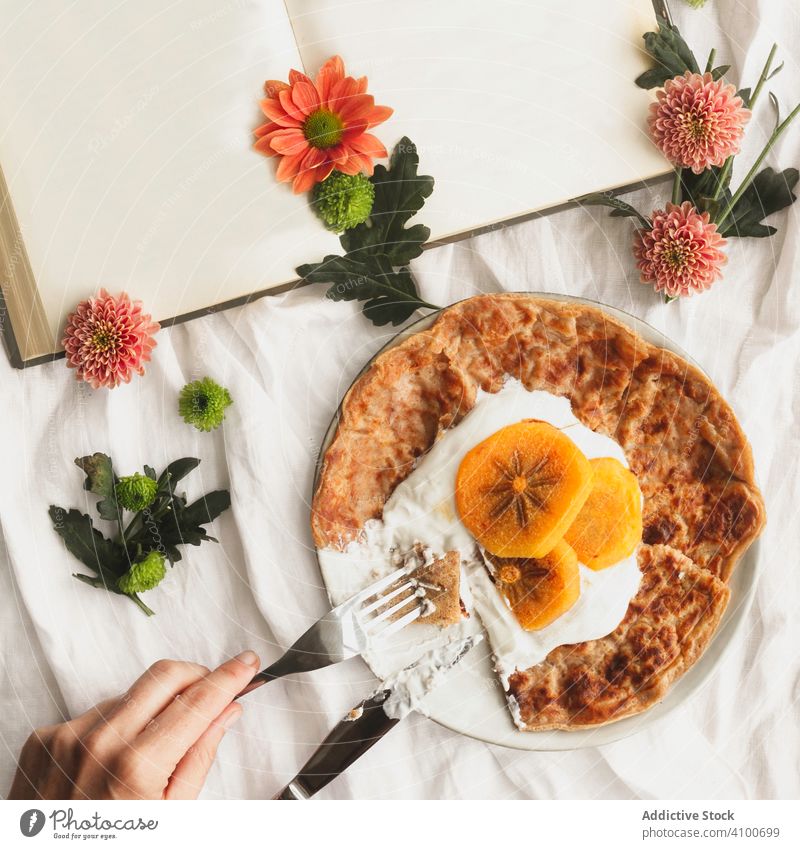 Crêpes mit Sahne und Kakipflaume Frucht Persimone Lebensmittel rötlich Dessert geschmackvoll Gabel Portion Messer Buch Blumen Scheibe lecker Teller Stoff