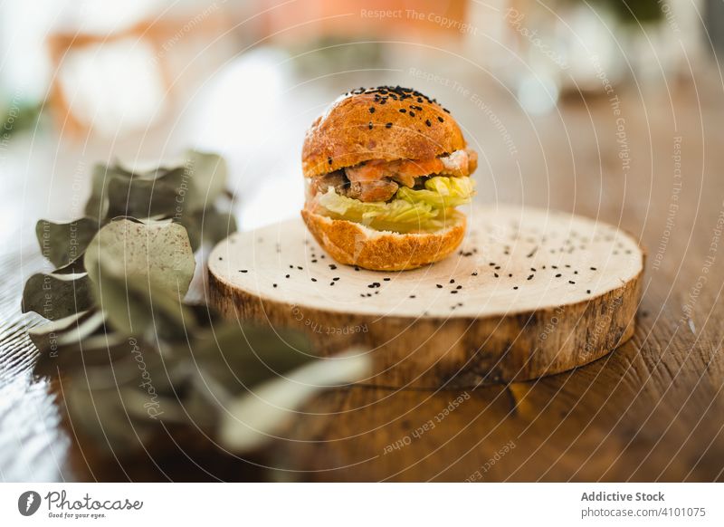 Leckerer Hamburger mit schwarzem Sesam auf Holztablett Burger Tablett Tisch hölzern rund Holzplatte Mahlzeit Lebensmittel Fastfood Abendessen Junk Food Fleisch