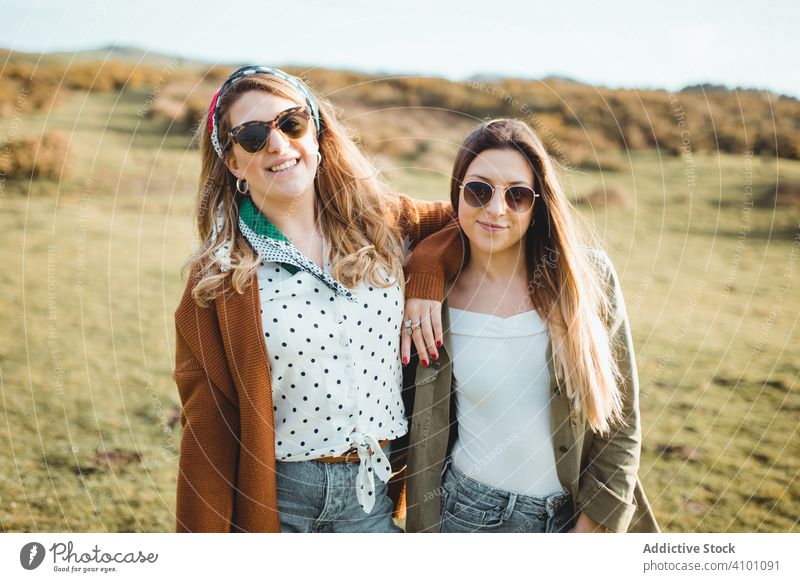 Stilvolle fröhliche Frauen auf grüner Wiese stehend Feld Glück Schwester Harmonie Landschaft Frühling Zusammensein Natur schließen reisen Tourismus Reise