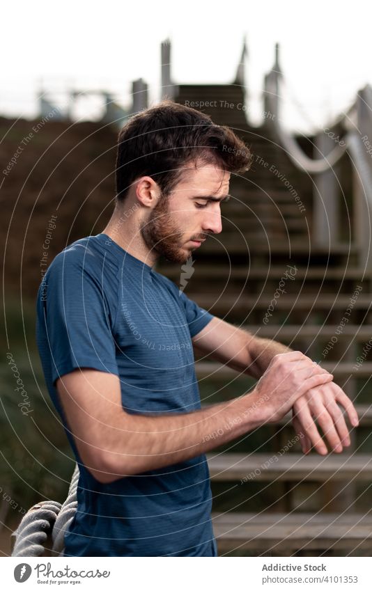 Sportler in Sportkleidung schaut auf einer Treppe auf seine Armbanduhr Überprüfung intelligente Uhr Handgelenk Zeit Stehen hölzern Zeitschaltuhr Lifestyle