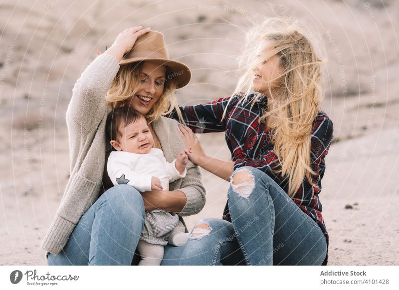 Fröhliche Frauen ruhen sich mit Baby in der Natur aus neugeboren Spaziergang Spaß Wind Lächeln Glück heiter Lifestyle modern Kind Bonden Liebe Angebot lässig