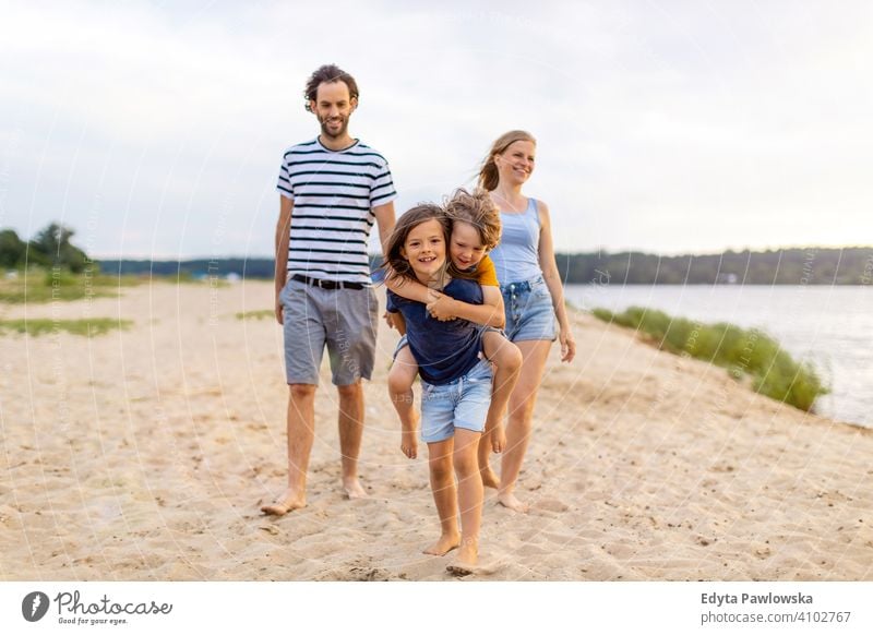 Junge Familie mit Spaß im Freien am Strand MEER See Feiertage Urlaub Natur Sommer Eltern Sohn Kinder Zusammensein Zusammengehörigkeitsgefühl Liebe Menschen