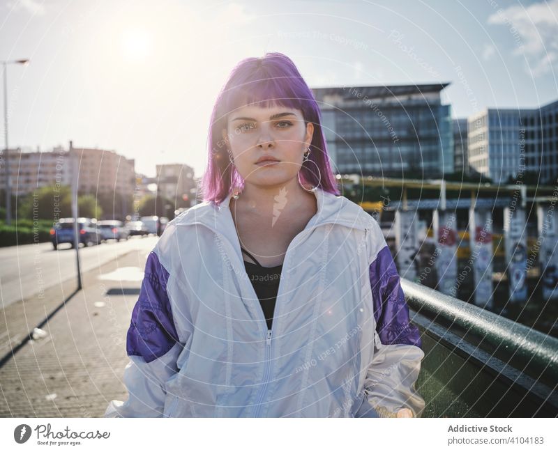 Frau mit violettem Haar lehnt an Metallzaun stylisch urban purpur Frisur Jacke Revier selbstbewusst Mode jung Stil Model Straße menschlich Außenseite Outfit