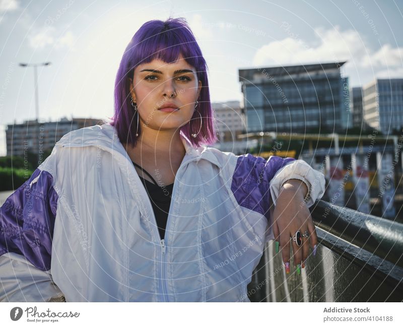 Frau mit violettem Haar lehnt an Metallzaun Lehnen stylisch urban purpur Frisur Jacke glänzend Zaun Revier selbstbewusst Mode jung Stil Model Straße menschlich