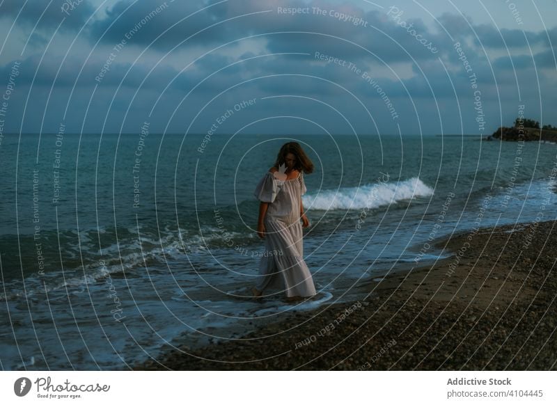 Weibliche Touristen am Meer Frau Strand Wellen Seeküste Barfuß Meeresufer Himmel Himmel (Jenseits) Abenddämmerung Wolken Dame laufen Küstenlinie leer einsam