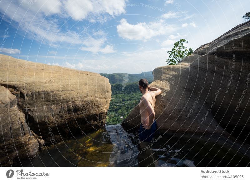 Erstaunter Mann genießt die Aussicht und schwimmt in einem steinigen Becken in einem Wasserfall in den Bergen Schwimmsport Pool Erholung Spaß Urlaub