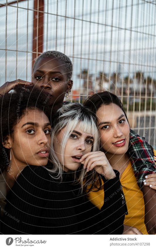 Diverse Gruppe von lächelnden Frauen, die sich auf dem Rasen umarmen Freund umarmend Menschengruppe Lächeln Lachen Kuscheln lässig Spaß Zusammensein jung