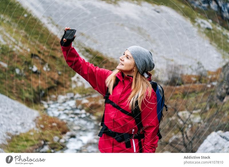 Frau mit Rucksack nimmt sich auf dem Smartphone auf dem Hintergrund der Berge mit Tourist Selfie Berge u. Gebirge benutzend reisen Natur Gerät Apparatur