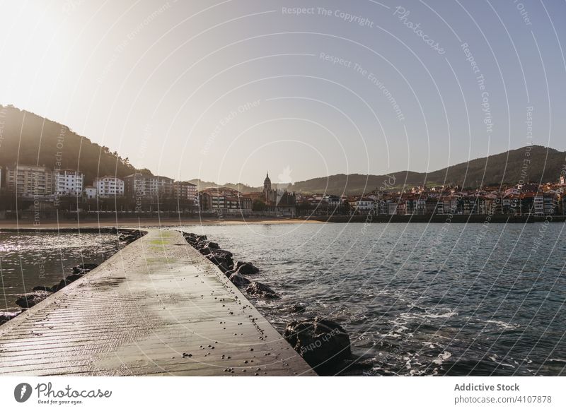 Nasser Steg, der zum Ufer der Küstenstadt führt, an einem sonnigen Sommertag Pier Hafengebiet MEER Wasser Stadt Hügel Felsbrocken Küstenstreifen Tourismus