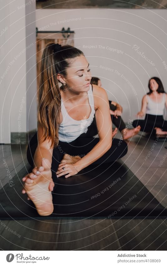 Fit weiblichen Athleten Stretching Beine in janu sirsasana Position beim Üben von Yoga in modernen Studio Training Übung beweglich Fitness üben Janu Sirsasana