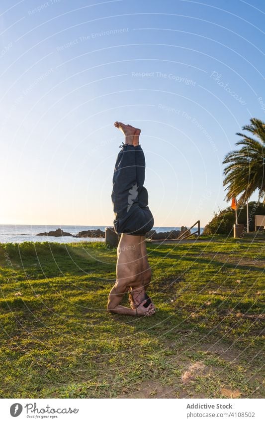 Starker Mann macht Yoga am schönen Strand des Ozeans Körperhaltung Meeresufer Natur Blauer Himmel Handfläche tropisch exotisch Gleichgewicht Dehnung Paradies