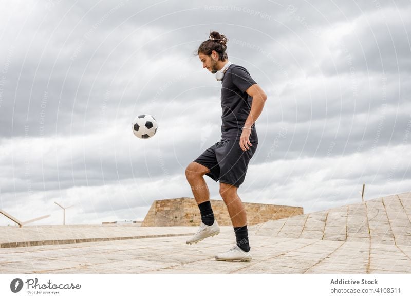 Mann trainiert mit Fußball gegen bewölkten Himmel Ball Kick wolkig Großstadt urban Straße Sport männlich Sportler Spiel Aktivität Training Spieler Athlet