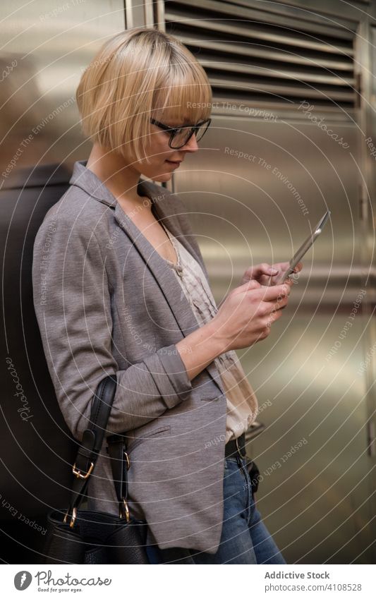 Frau lehnt sich an die Wand und benutzt ein Tablet Geschäftsfrau stylisch jung Tablette Lehnen professionell Person schön attraktiv Unternehmer elegant