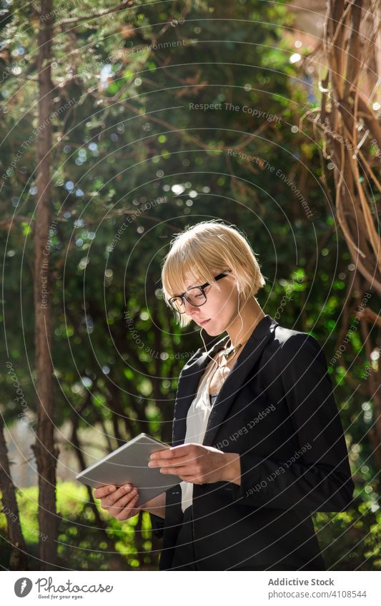 Junge Geschäftsfrau benutzt Tablet auf der Straße Kopfhörer stylisch jung Tablette Browsen zuschauend Park Frau professionell Person schön attraktiv Unternehmer