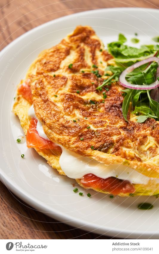 Leckere gebratene Tortilla mit Salat Fisch Salatbeilage gefüllt rot Teller Saucen Sahne Käse Meeresfrüchte Haute Cuisine Restaurant Zwiebel Kraut grün golden