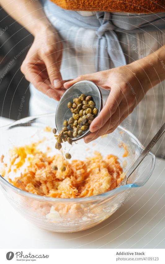 Frau gibt Kapern in die Schüssel mit der Füllung Essen zubereiten Kapriolen Bestandteil hinzufügen mischen Lebensmittel Rezept Fisch Lachs mariniert grün Küche