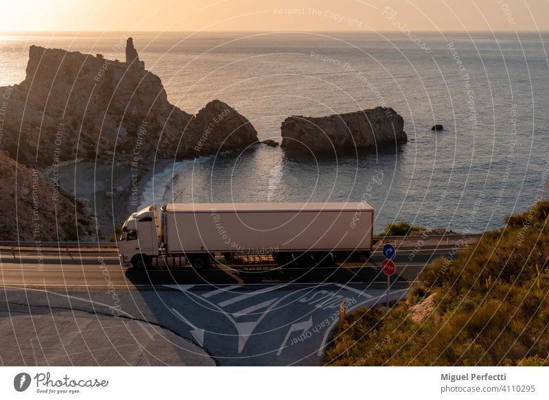 Lkw mit Kühlsattelauflieger fährt auf einer Straße neben einem Strand. camion Refrigerado montaña Farbfoto Menschenleer Natur blau Karretera Playa mar Islote