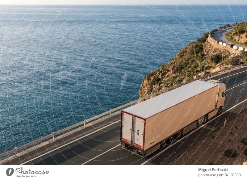 LKW mit Kühlsattelauflieger fährt auf einer Straße am Meer. camion Refigerado Temperaturregler Logística Transporte Transportar paisaje mar azul Vertrieb