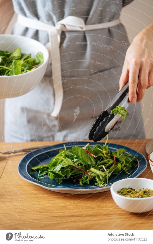 Erntefrau legt Kräuter auf den Teller Frau Salatbeilage Kraut Koch setzen Zange Gesundheit Küche Speise Lebensmittel Vorbereitung heimwärts Mahlzeit Bestandteil