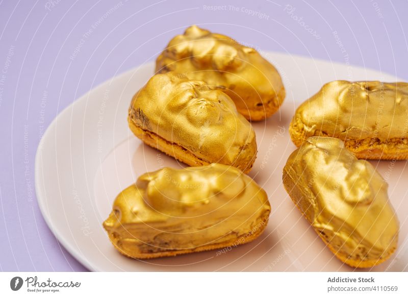 Leckere Eclairs mit goldener Glasur Dessert eclair Zuckerguß Teller süß Lebensmittel Gebäck geschmackvoll Küche Speise lecker Kalorie Portion gebacken