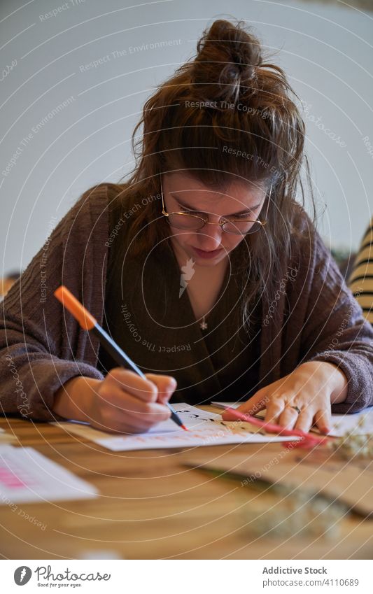 Künstlerin zeichnet mit Bleistift im Kunstatelier Frau Beschriftung Handschrift zeichnen Konzentration kreativ Fokus Lifestyle lernen Job sitzen Skizze