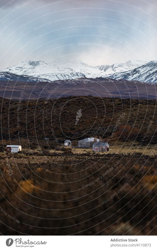 Kleine Siedlung in der Ebene vor Bergkämmen bei bedecktem Himmel Berge u. Gebirge Haus Horizont Vorberg reisen Wohnsiedlung Kamm Top Land Einsamkeit Hochland