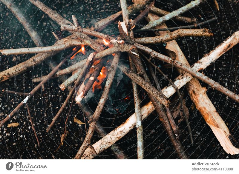 Kleines Lagerfeuer aus Brennholz am Boden Freudenfeuer Rauch aufflackern kleben Ast Natur erwärmen Flamme Brandwunde heiß Energie warm Feuerstelle Dunst