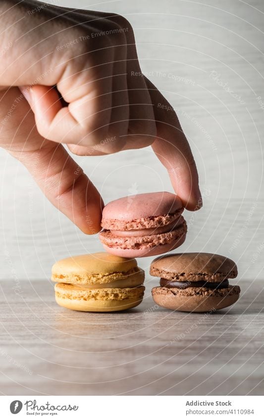 Crop Hand platziert Makronen auf dem Tisch Mann Platzierung Finger Haufen Biskuit frisch geschmackvoll Keks hell Bestandteil Lebensmittel gebacken süß Snack